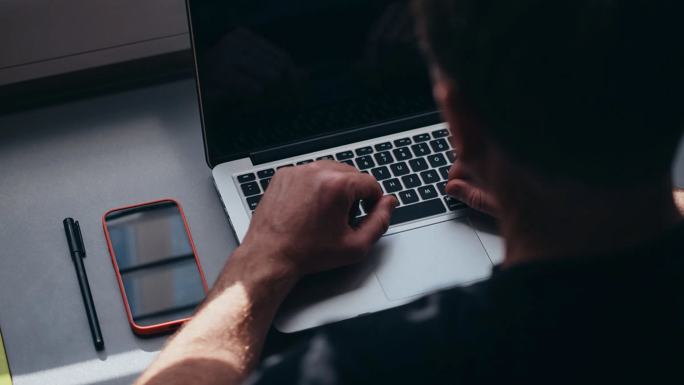 Mains sur le clavier d'un ordinateur portable, téléphone posé à côté